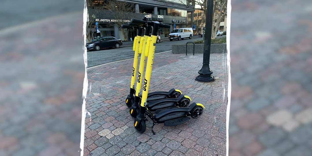 Bright yellow electric scooters set up in a row on a brick sidewalk
