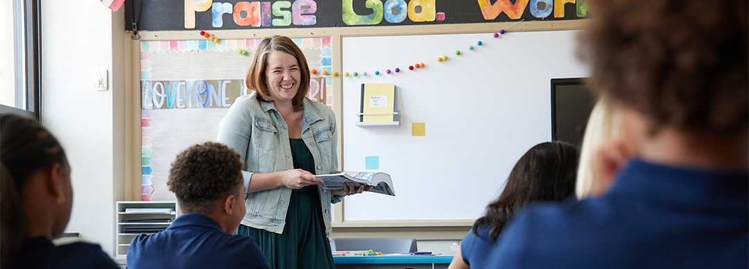 Teacher laughing with students at desks