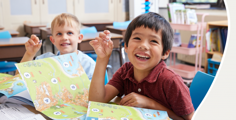 Boy smiling with a Go Seek Find activity booklet on desk