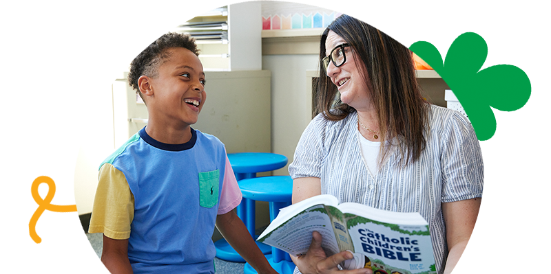 Young person smiling with his mentor reading The Catholic Children’s Bible